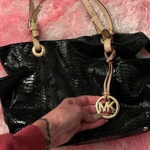 Michael Kors Black soft textured vegan shiny leather, tan handle, gold charm.